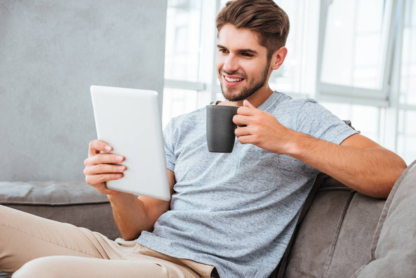 Cheerful man communication by tablet while drinking a coffee - Photo, Image