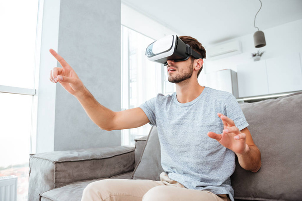 Young man wearing virtual reality device and pointing - Fotoğraf, Görsel