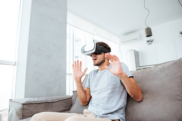 Shocked young man wearing virtual reality device - Foto, afbeelding