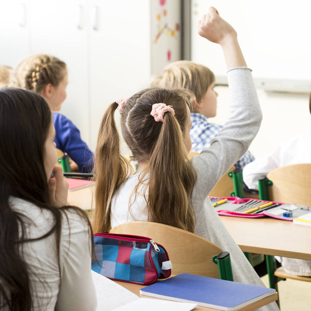 Girl raising her hand in school - Фото, зображення