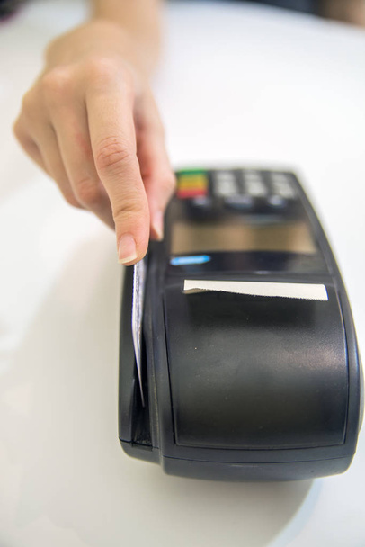 Hand swipe rode krediet via betaalterminal. Debet kaart jatten op pos terminal. credit card lezer machine op witte achtergrond - Foto, afbeelding