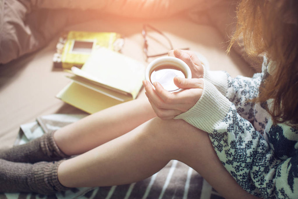 Девушка читает книгу в постели с теплыми носками пьет кофе
 - Фото, изображение