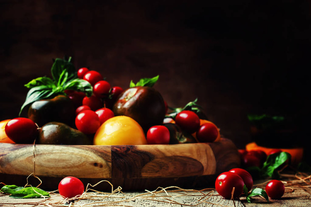Various tomatoes on old wooden table - Фото, зображення