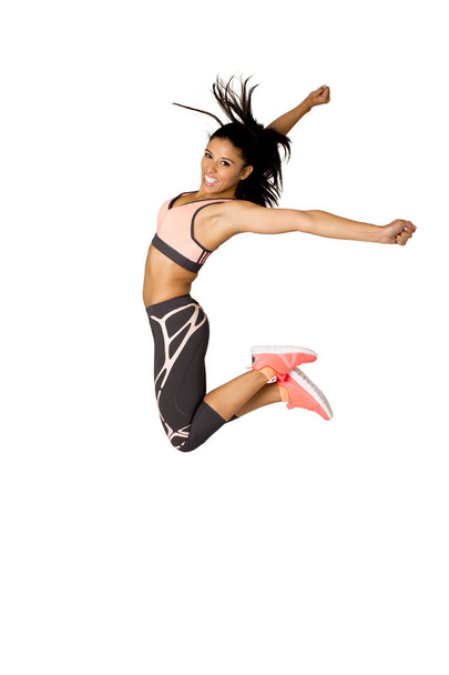 молодая привлекательная латиноамериканская тренер фитнес женщина прыгает высоко взволнованный и счастливый
 - Фото, изображение