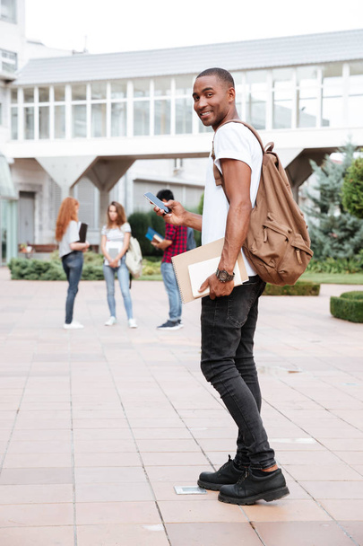 Smiling african man student with backpack walking in campus - Fotoğraf, Görsel