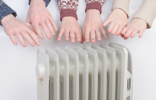 Família aquecendo as mãos sobre aquecedor elétrico
 - Foto, Imagem