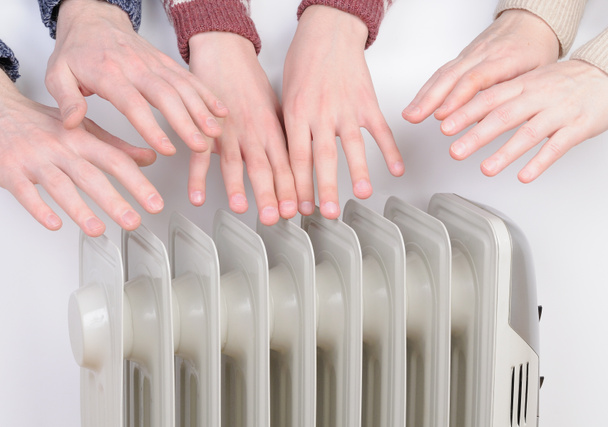 Family warming up hands over electric heater - Photo, Image