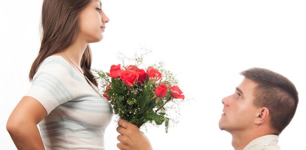 Jovem ajoelhado e dando buquê de rosas para sua namorada
 - Foto, Imagem