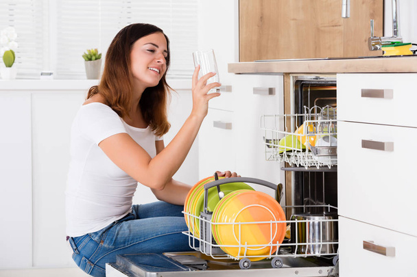 Woman taking drinking glass from dishwasher - Фото, изображение