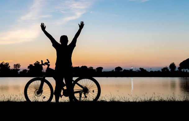 Silhouette Frau Hände oben mit Fahrrad auf Sonnenuntergang Hintergrund - Foto, Bild