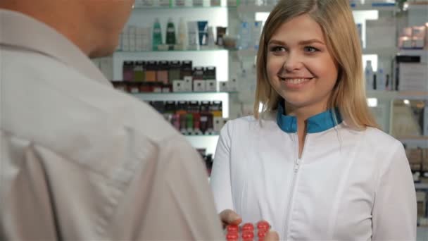 Γυναίκα φαρμακοποιό ρόμβους προσφέρει στον πελάτη με το φαρμακείο - Πλάνα, βίντεο