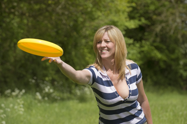 Γυναίκα ρίχνει ένα πλαστικό ιπτάμενο δίσκο - Φωτογραφία, εικόνα