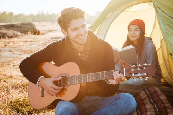 Young couple with guitar in tent - 写真・画像