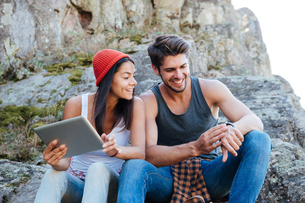Happy young couple sitting together with tablet and using smartwatch - Fotoğraf, Görsel