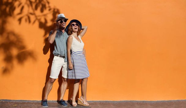 smiling couple near orange wall  - Фото, зображення