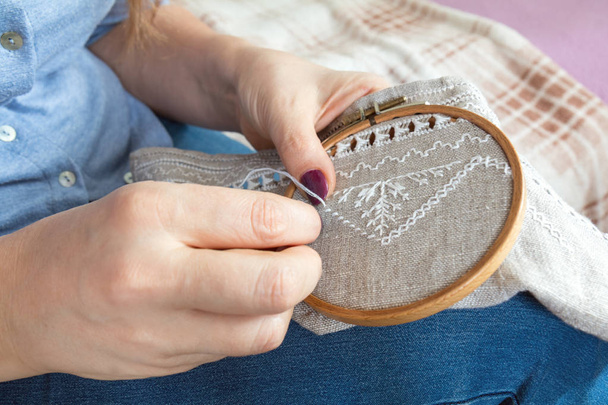 Vrouw handen doen opengewerkte borduurwerk op homespun linnen.  - Foto, afbeelding