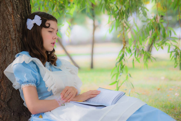 Niña alumna cayó sueño bajo un árbol con un libro
. - Foto, Imagen