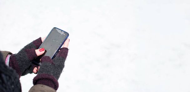 Γυναικεία χέρια χρησιμοποιώντας ένα smartphone το χειμώνα - Φωτογραφία, εικόνα