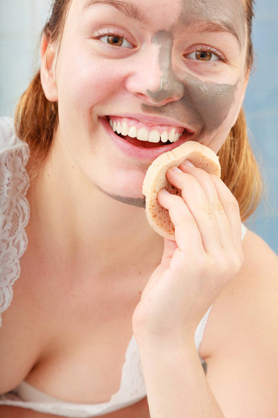 woman removing facial clay mud mask in bathroom - Φωτογραφία, εικόνα