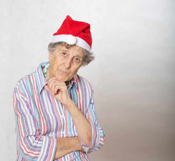 Velha mulher no chapéu de um Papai Noel
 - Foto, Imagem