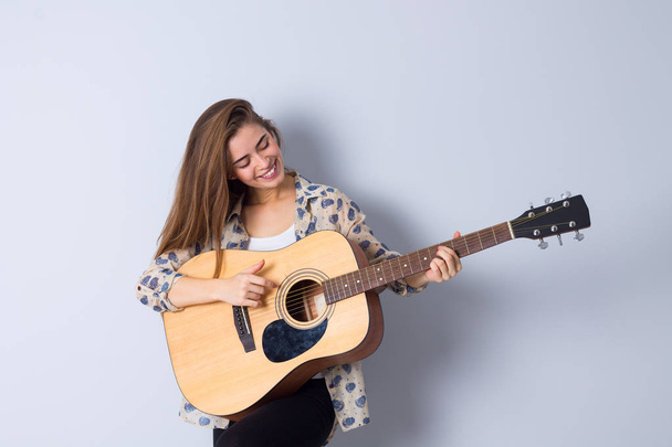 Young woman holding a guitar - Foto, Imagen