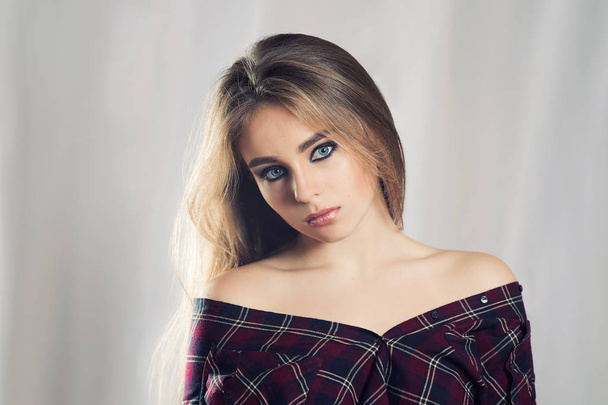 High quality portrait of a girl on a light background. Female Studio portrait. Natural beauty lady. Bright makeup. Smokey eyes makeup. Brown hair. Girl in plaid shirt. - Foto, Bild