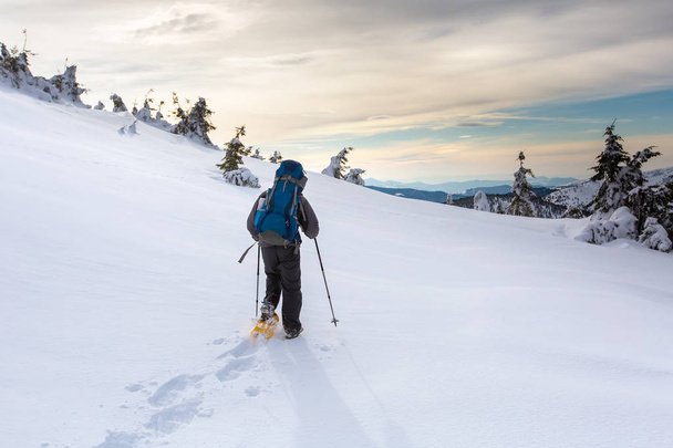Mies vaeltaa talvella vuorilla ennen ukkosta
 - Valokuva, kuva