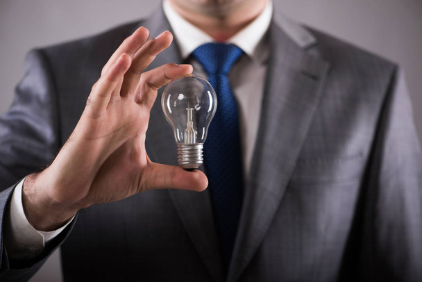 Бізнесмен тримає лампочку в концепції творчості
 - Фото, зображення