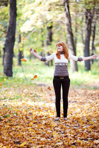 молодий рудий підліток кидає листя жінки в лісі
 - Фото, зображення