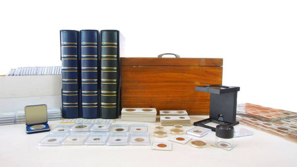Coins of different countries of the world on white table with folders and supplies background - Numismatic scene - Photo, Image