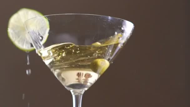 An olive falling into the goblet with the alcohol and slice of the lime. Slowly - Felvétel, videó