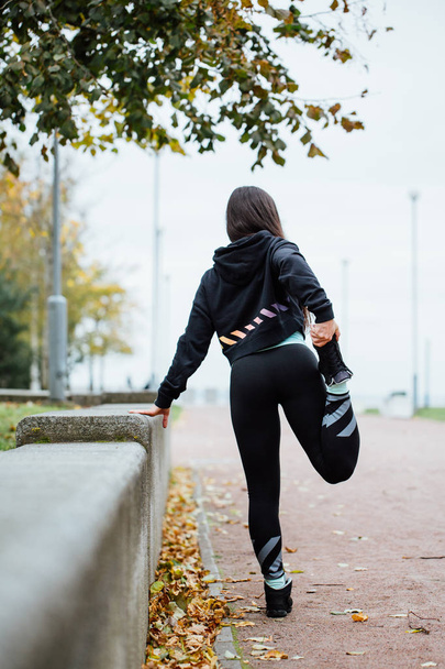 Woman runner stretching legs before run. - Foto, afbeelding
