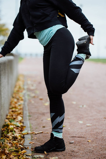 Woman runner stretching legs before run. - Фото, изображение