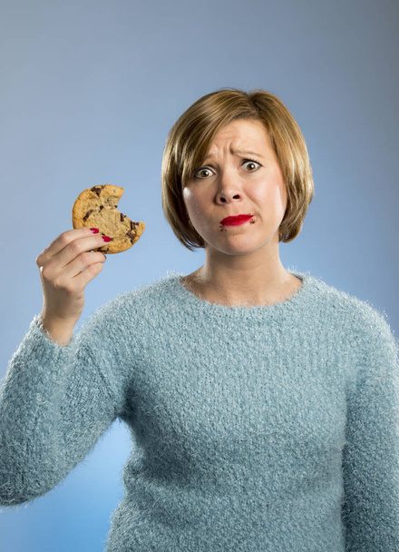  cute beautiful woman with chocolate stain in mouth eating big delicious cookie - Photo, Image