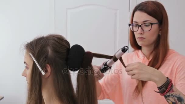 2 shots. Professional hairdresser doing hairstyle for young pretty woman - Footage, Video