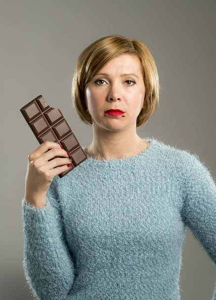 mujer sosteniendo gran barra de chocolate con manchas en la boca y cara culpable expresión en la adicción al azúcar
 - Foto, Imagen