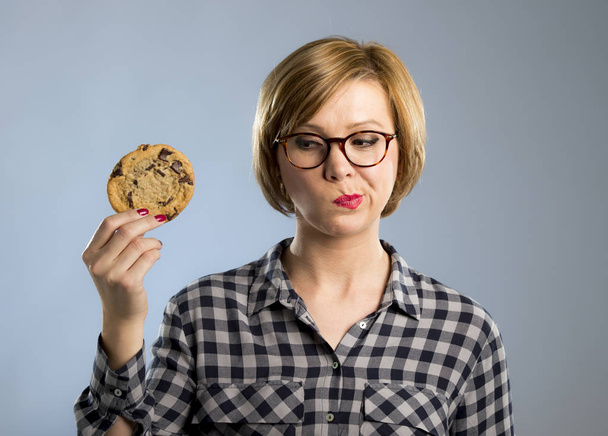 young blond cute and friendly caucasian woman in casual clothes holding big delicious chocolate cookie  - Photo, Image