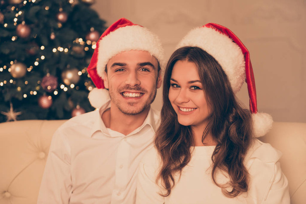 Portrait of pretty smiling man and woman in red santa hats - Фото, изображение