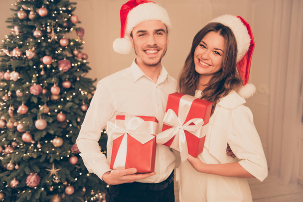 Happy young couple celebrating Christmas   and holding red prese - Фото, зображення