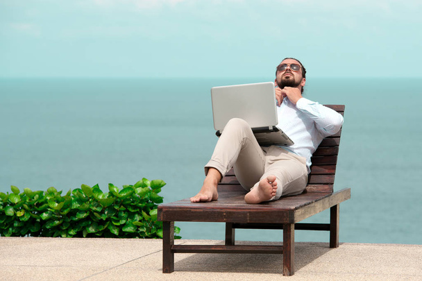 Liikemies yllään puku kannettavan tietokoneen rannalla
 - Valokuva, kuva