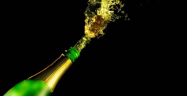 Celebration theme with splashing champagne, isolated on black background - Photo, Image