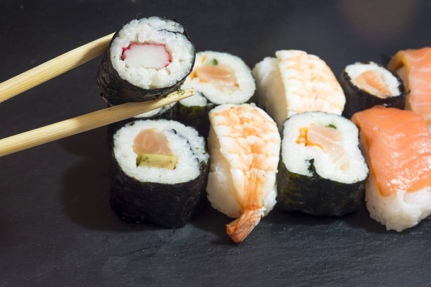 Pedaços de sushi em uma pedra preta
 - Foto, Imagem