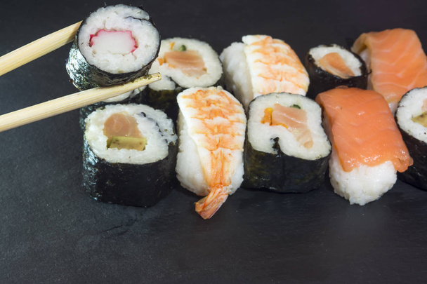Stukken van sushi op een zwarte steen - Foto, afbeelding