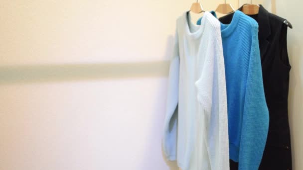 Allmählich entstehen bunte Kleider und Pullover auf dem Kleiderbügel - Filmmaterial, Video