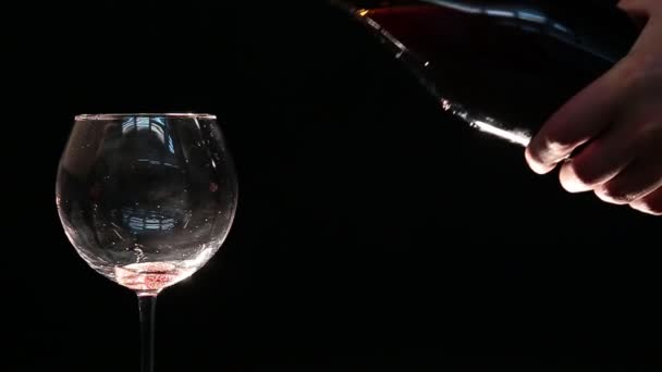 このビデオでは、匿名の手は黒い背景を持つガラスに赤ワインのずさんなと汚い注ぎを作ります. - 映像、動画