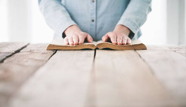 hands praying with a bible over wooden table - Foto, immagini