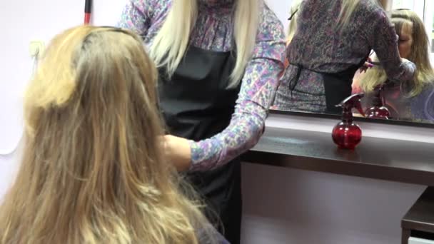 Peluquería peinando cabello de cliente femenino frente al espejo. Cambio de enfoque. 4K
 - Imágenes, Vídeo