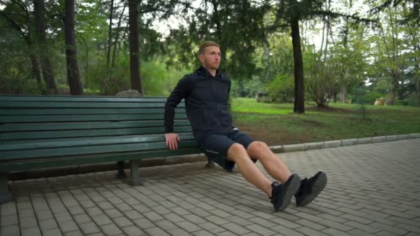 Mies terveellistä elämäntapaa tehdä penkki push ups kaupungin puistossa hidastettuna
 - Materiaali, video
