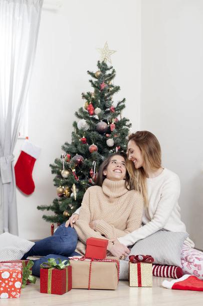 women next to Christmas tree with Christmas presents - Foto, Imagen
