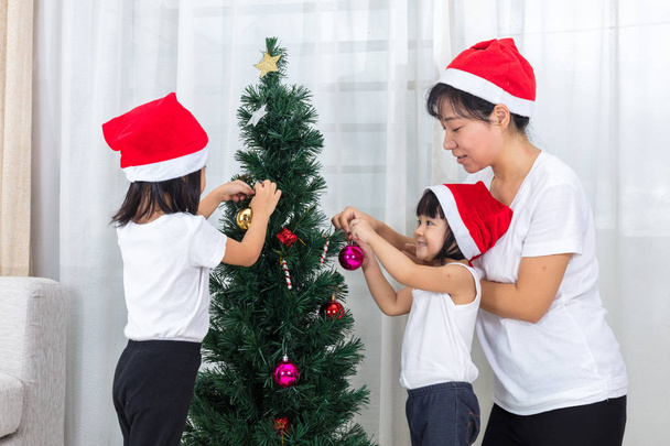 Asian Chinese mother and daughters decorating Christmas tree at  - Фото, зображення